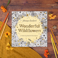 Load image into Gallery viewer, Coloring book titled 'Wonderful Wildflowers' by Johanna Basford on a wooden surface with flowers and pencils.