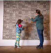 Load image into Gallery viewer, Two people examining a large patterned fabric on a wall.