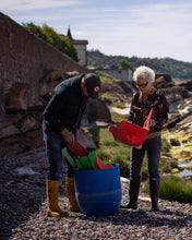 Load image into Gallery viewer, Anna Campbell Jones and Ally Mitchell, with buckets of washed up ocean plastic and tools on a rocky outdoor area.