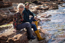 Load image into Gallery viewer, Anna Campbell Jones and Ally, Ocean Kitchen Scotland sitting on rocks by the sea wearing rain boots.