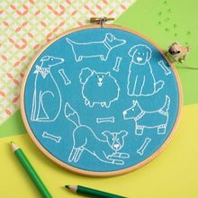 Load image into Gallery viewer, Embroidery hoop with white dog illustrations on blue fabric, surrounded by green pencils and a small dog toy.