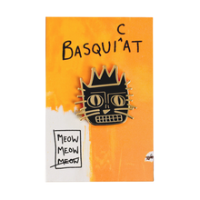 Load image into Gallery viewer, Enamel pin with a cat face design on a Basquicat branded card