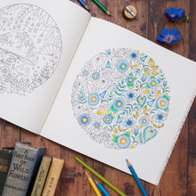 Load image into Gallery viewer, Adult colouring book with floral design on a wooden surface with colouring pencils and books.