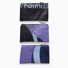 Load image into Gallery viewer, Close-up of three recycled exhibition banner A5 zip pouch showing purple and blue graphic artwork.