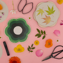 Load image into Gallery viewer, Flower press details of floral and leaf designs on a pink background with scissors and flowers.