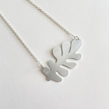 Load image into Gallery viewer, close up detail of silver abstract leaf-shaped necklace pendant by tom pigeon