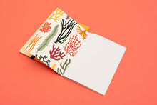 Load image into Gallery viewer, Notebook with colourful seaweed illustrations on a coral background
