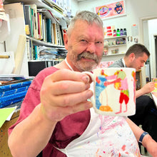 Load image into Gallery viewer, Arthouse Unlimited artist holding Hugging Animals illustrated bone china mug, showcasing ethical art gift design.
