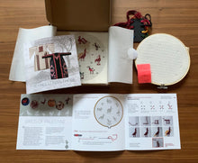Load image into Gallery viewer, Embroidery hoop with pattern book and brochures on a wooden surface
