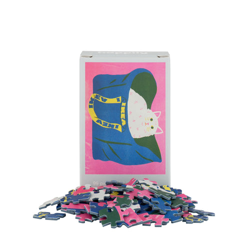 Puzzle box with a cat design on a pink background, surrounded by puzzle pieces.