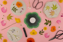 Load image into Gallery viewer, Decorative pressed flowers on flower press with floral and leaf designs on a pink background with scissors.
