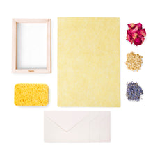 Load image into Gallery viewer, A collection of items for a flower paper crafting kit, including a wooden frame, a yellow piece of paper, a sponge, dried flowers, and four envelopes, all laid out on a white background.
