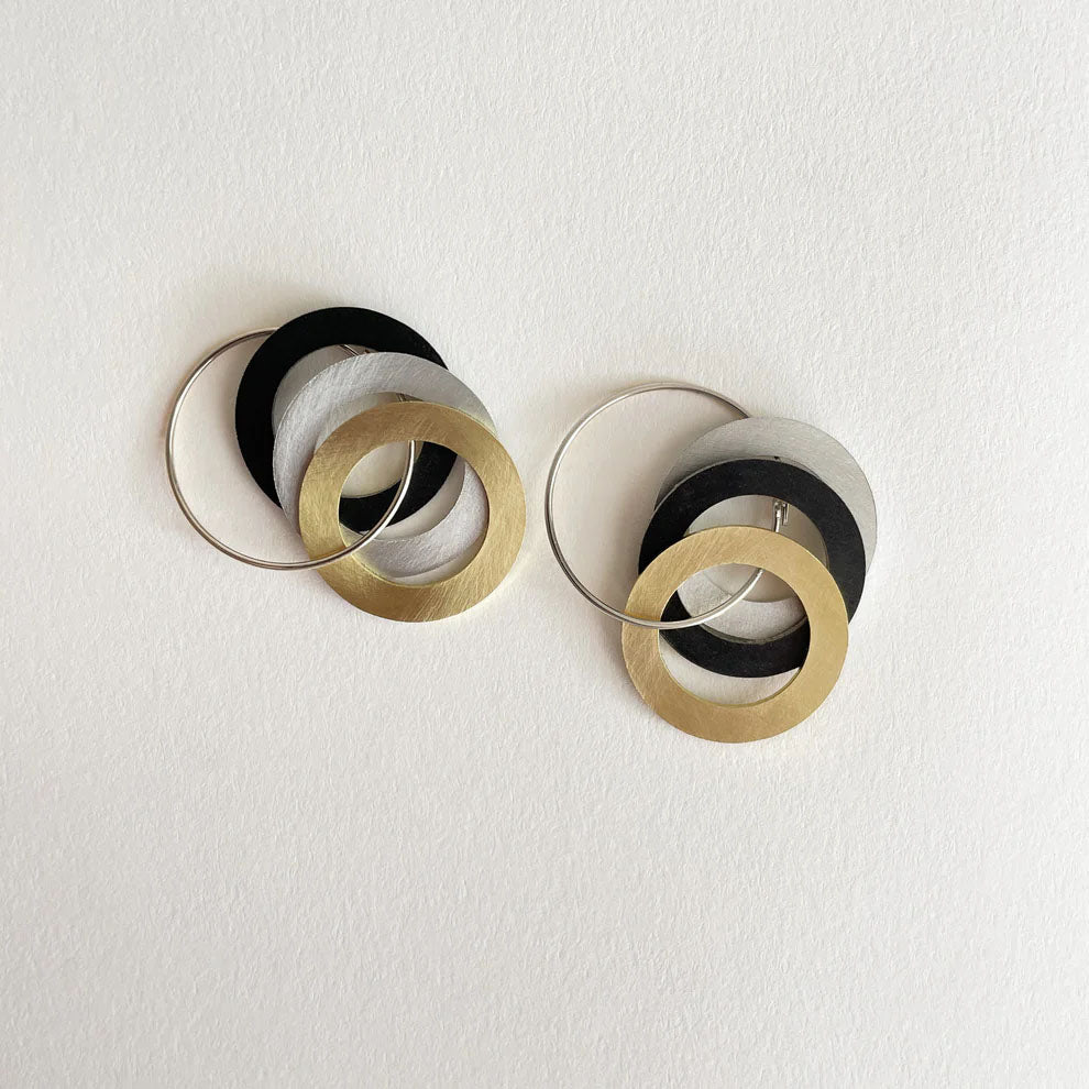 Pair of hoop earrings with interlocking circular design in mixed metals gold, silver, black on a white background