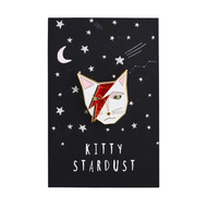Enamel pin of a cat with red and gold design on a black card with star and moon illustrations, labelled 'Kitty Stardust'.