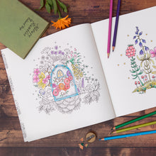 Load image into Gallery viewer, Adult colouring book with floral designs on a wooden surface with coloured pencils.
