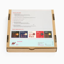 Load image into Gallery viewer, Cardboard box with tatreez embroidered fabric samples and brand information on a white background
