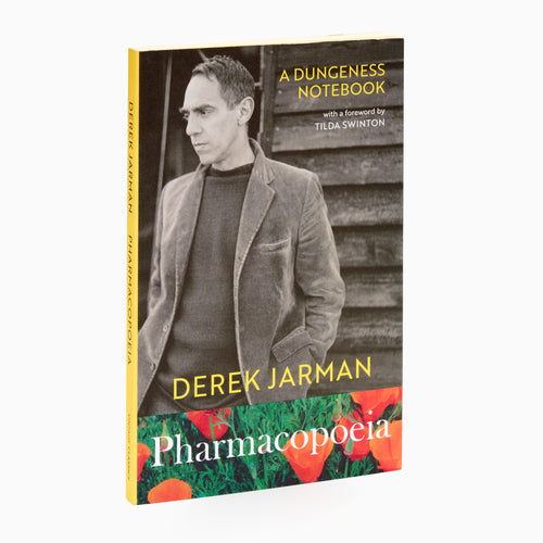 A cover image of the book 'Pharmacopioeia: A Dungeness Notebook' by Derek Jarman, featuring a photograph of the author with a background of a garden.