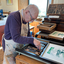 Load image into Gallery viewer, Artist Robbie Burns working on a printmaking project at a studio desk
