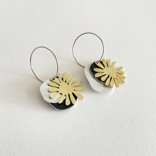 Pair of Tom PIgeon earrings with gold and black floral designs on a white background