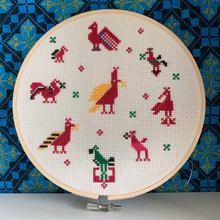Load image into Gallery viewer, Cross-stitched hoop with colorful animal patterns on a blue patterned fabric background
