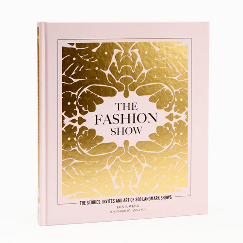 A hardcover book titled 'The Fashion Show' with a gold and white floral pattern on the cover.