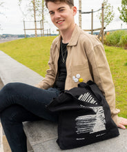 Load image into Gallery viewer, Person carrying tote bag featuring the architectural sketch of V&amp;A Dundee by Japanese architect Kengo Kuma.
