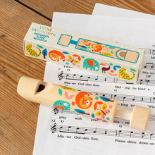 Load image into Gallery viewer, Wooden slide whistle with colorful animal designs on a sheet of music, next to its packaging.

